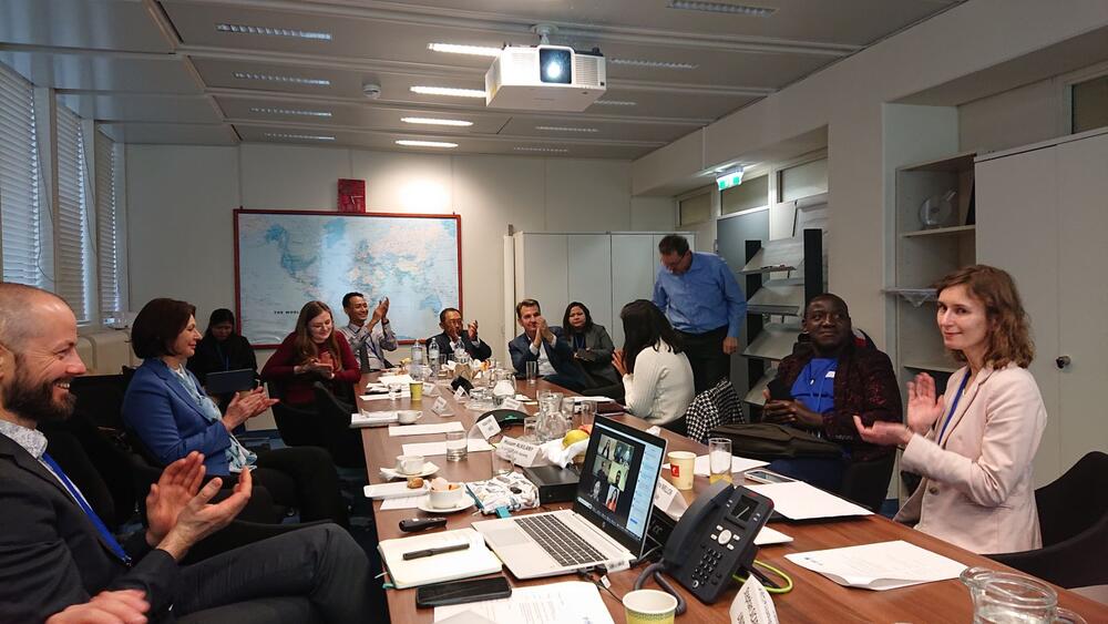 An image of the conference table at UNIDO headquarters showing group members clapping at the end of the meeting.